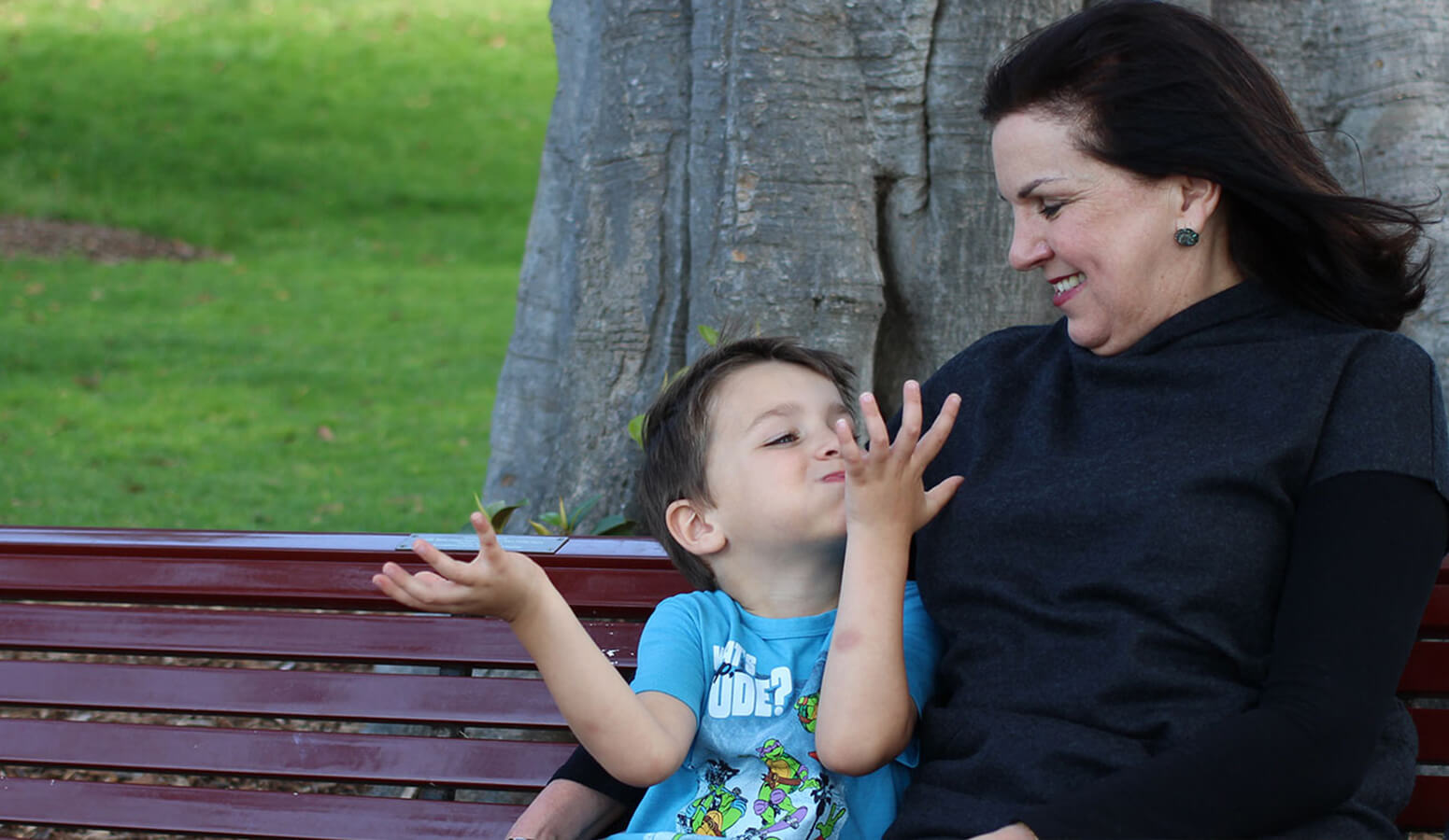 Woman and child cuddle on a park bench