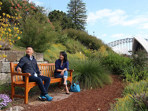 two people sit on a bench with sydney opera house in background