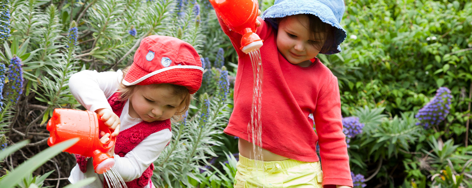Two young children watering plants during Nature Play