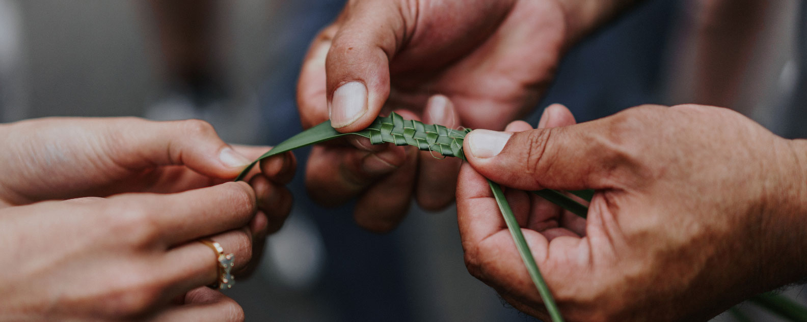 Two people holding a piece of woven plant fibre in their hands