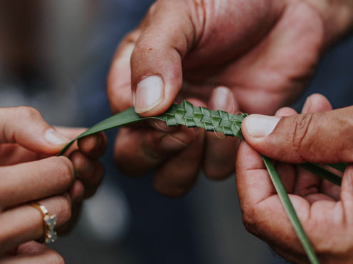 Two people holding a piece of woven plant fibre in their hands