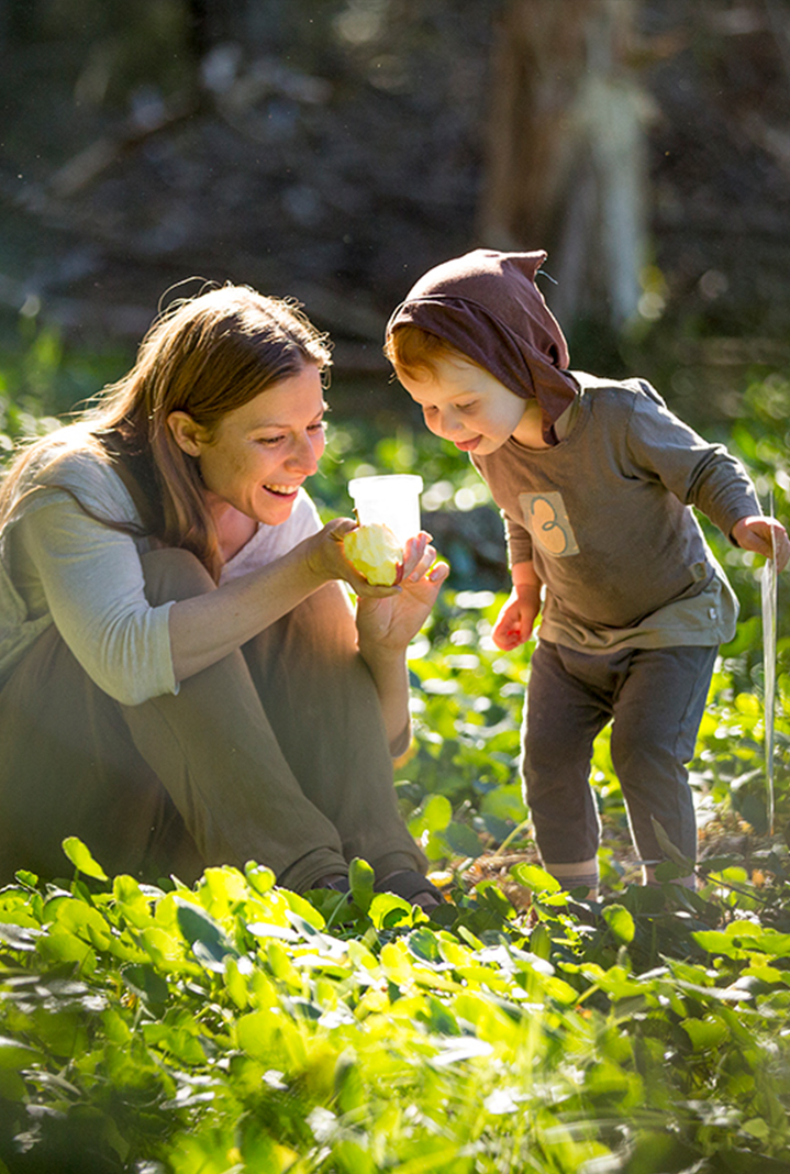 Guide and child in a nature area, examining a clear cup with an insect