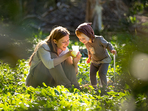 Guide and child in a nature area, examining a clear cup with an insect