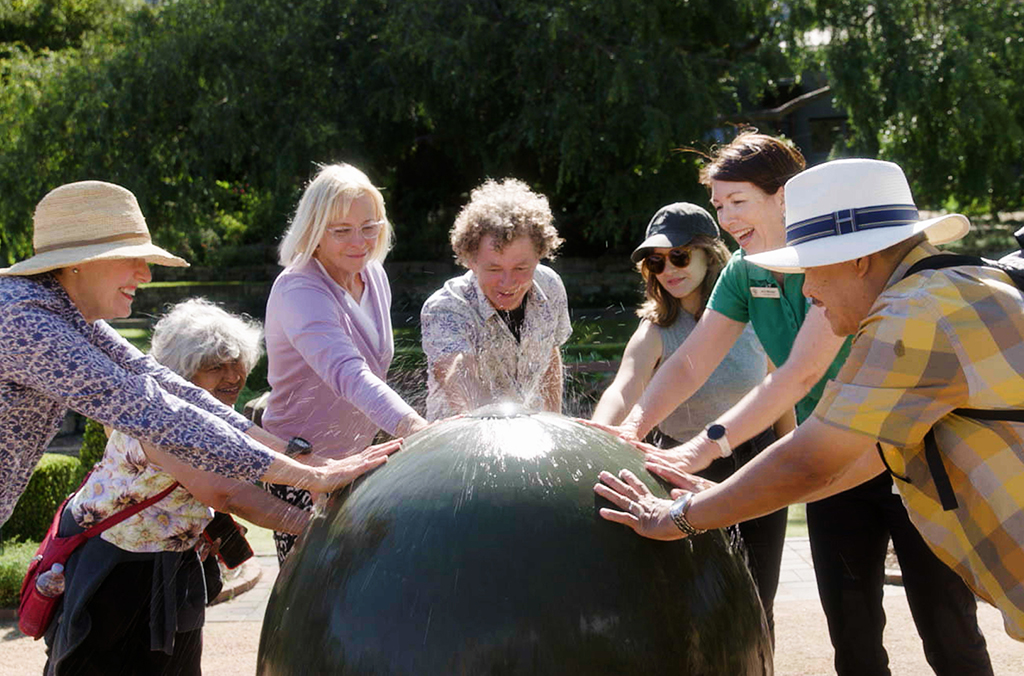 laughing people touching a water sculpture