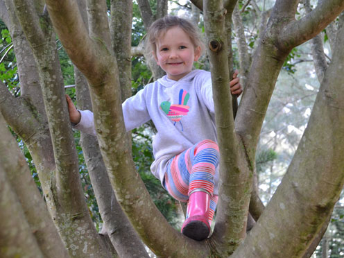 Young-girl in pink-boots-and-mauve-top-climbing-tree
