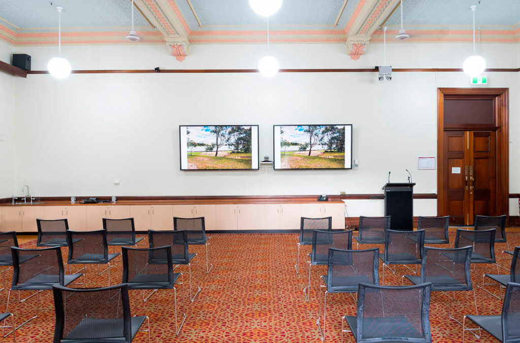 INterios of Victorian-era room with seating and two presentation flat screens with landscape images on them..