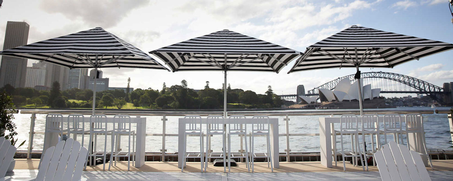 Three umbrellas at the harbourseide location, Fleet Steps in the Royal Botanic Garden Sydney, the Harbour Bridge is n the background.