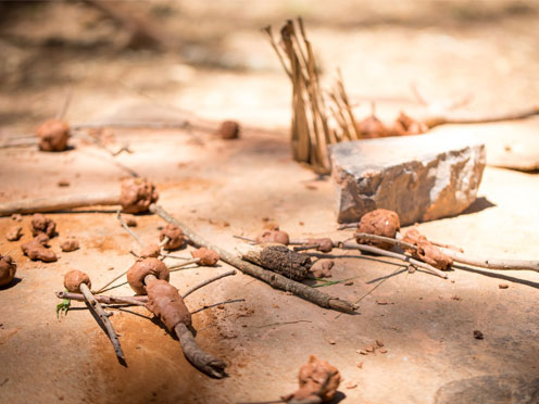 A range of different sticks, some with clay wrapped around them, sitting on a piece of sandstone 