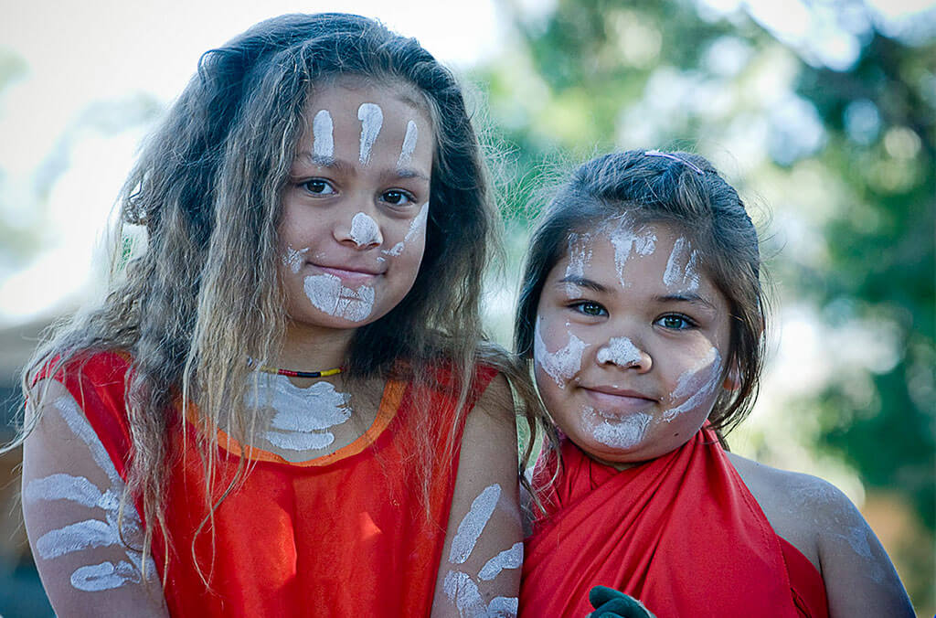 Two girls smiling with Aboriginal body art on their face and arms