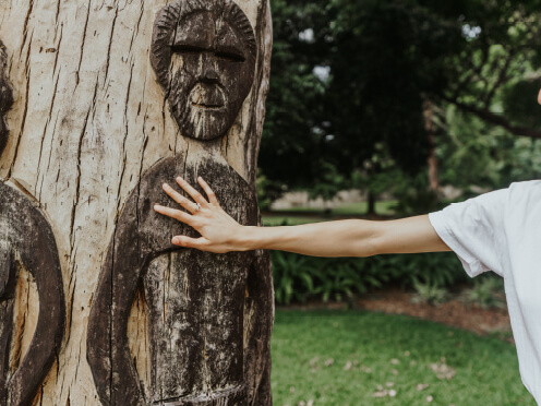 Sculpture of people on a tree, hand touching tree.