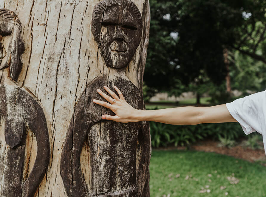 Sculpture of people on a tree, hand touching tree.