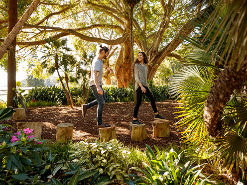 two people walk through a tropical garden