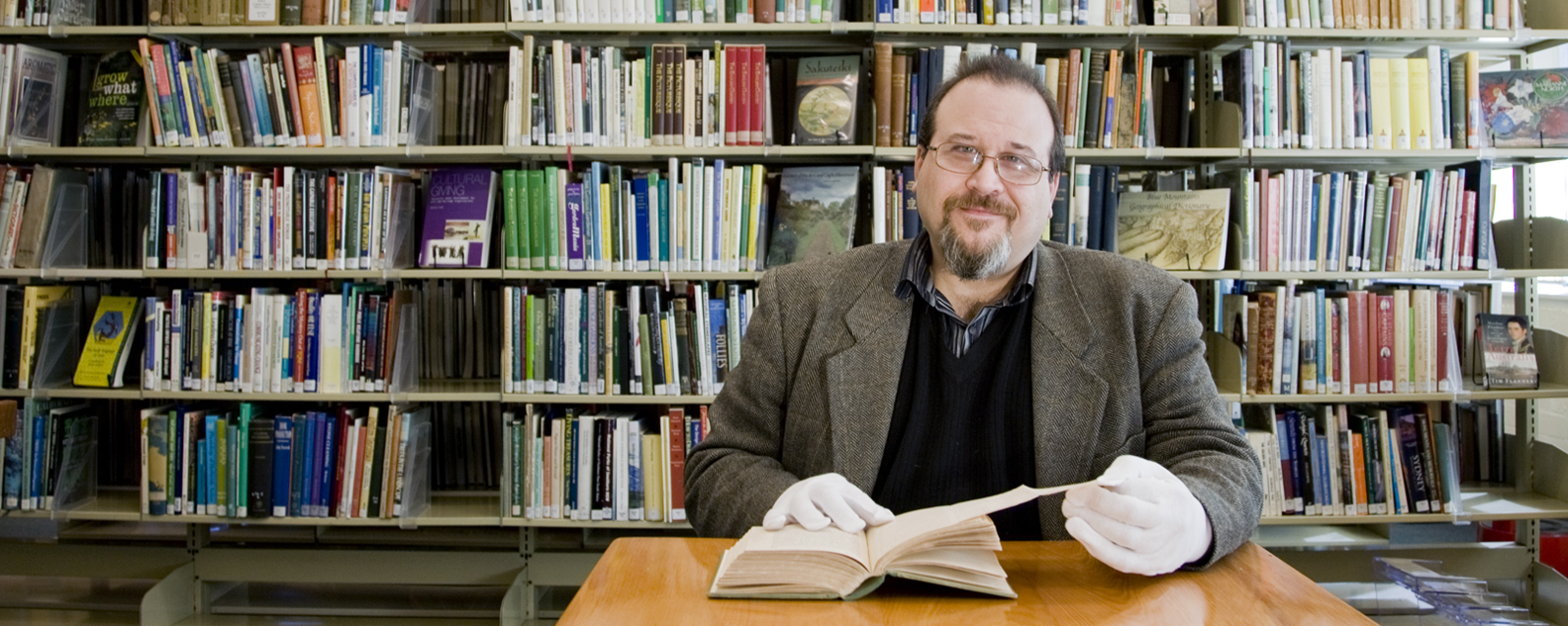 Librarian with an old book, bookshelves behind