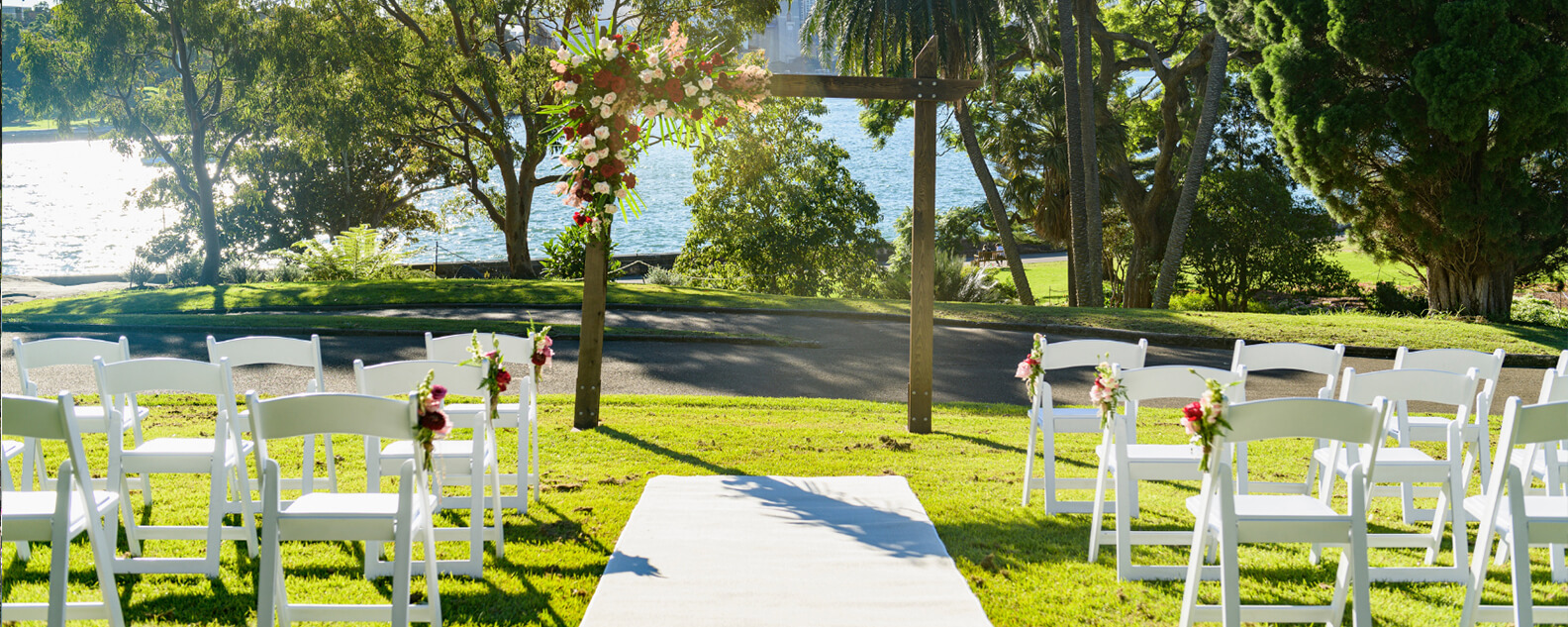 Lawn with wedding arch and white chairs, overlooking Sydney Harbour