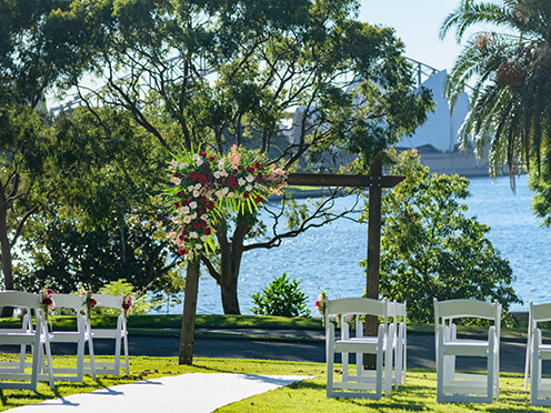 Lawn with wedding arch and white chairs, overlooking Sydney Harbour