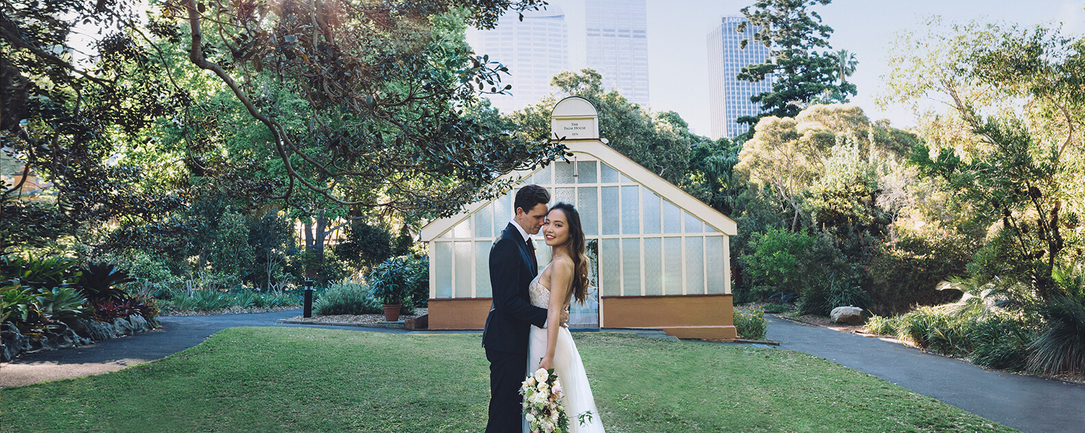 Bride and groom cuddle in front of historic, shabby chic green house wedding venue