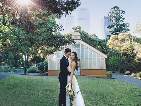 Bride and groom cuddle in front of historic, shabby chic green house wedding venue