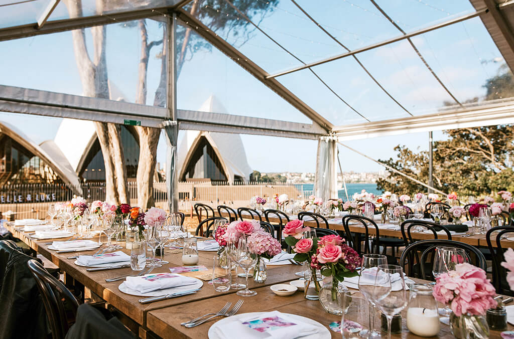 Elegant dining table with fresh flower placements in marquee overlooking Sydney Opera House