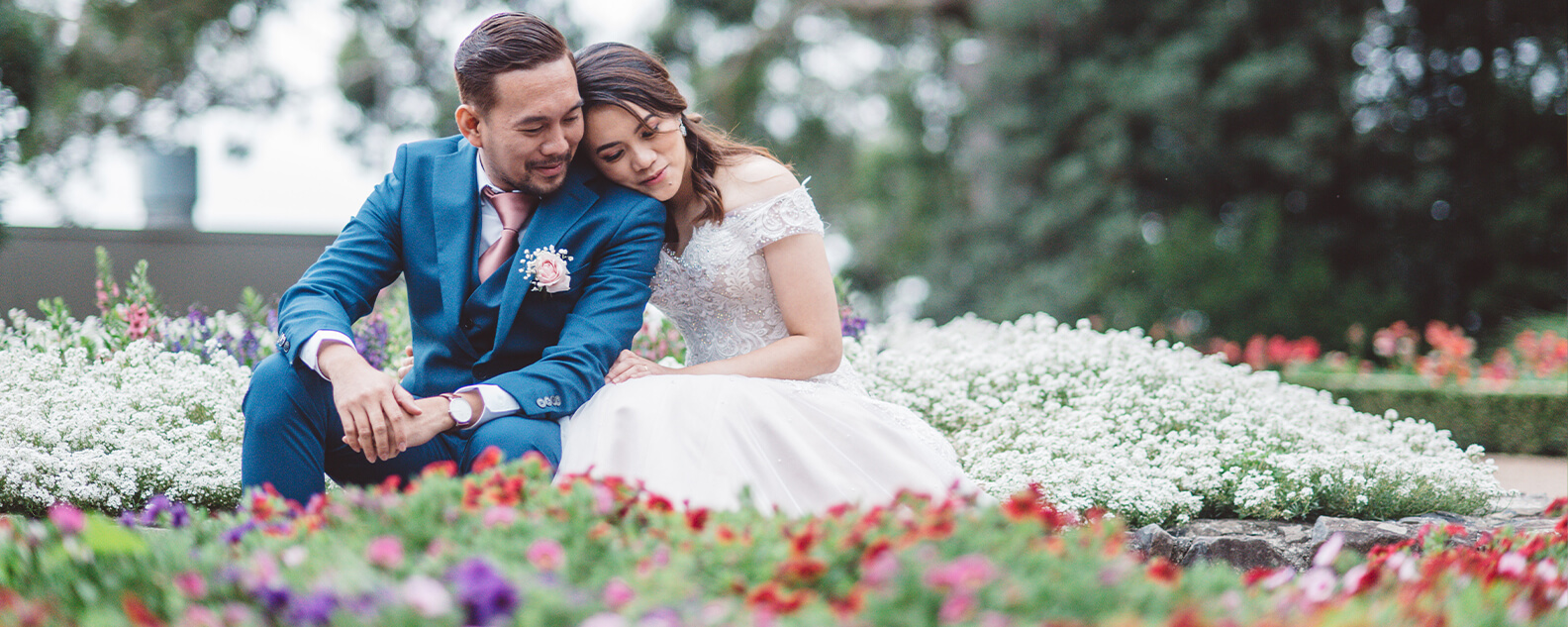 Bride and groom cuddle among bright spring flowers