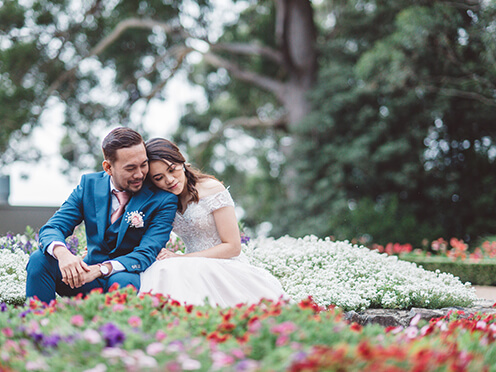 Bride and groom cuddle among bright spring flowers