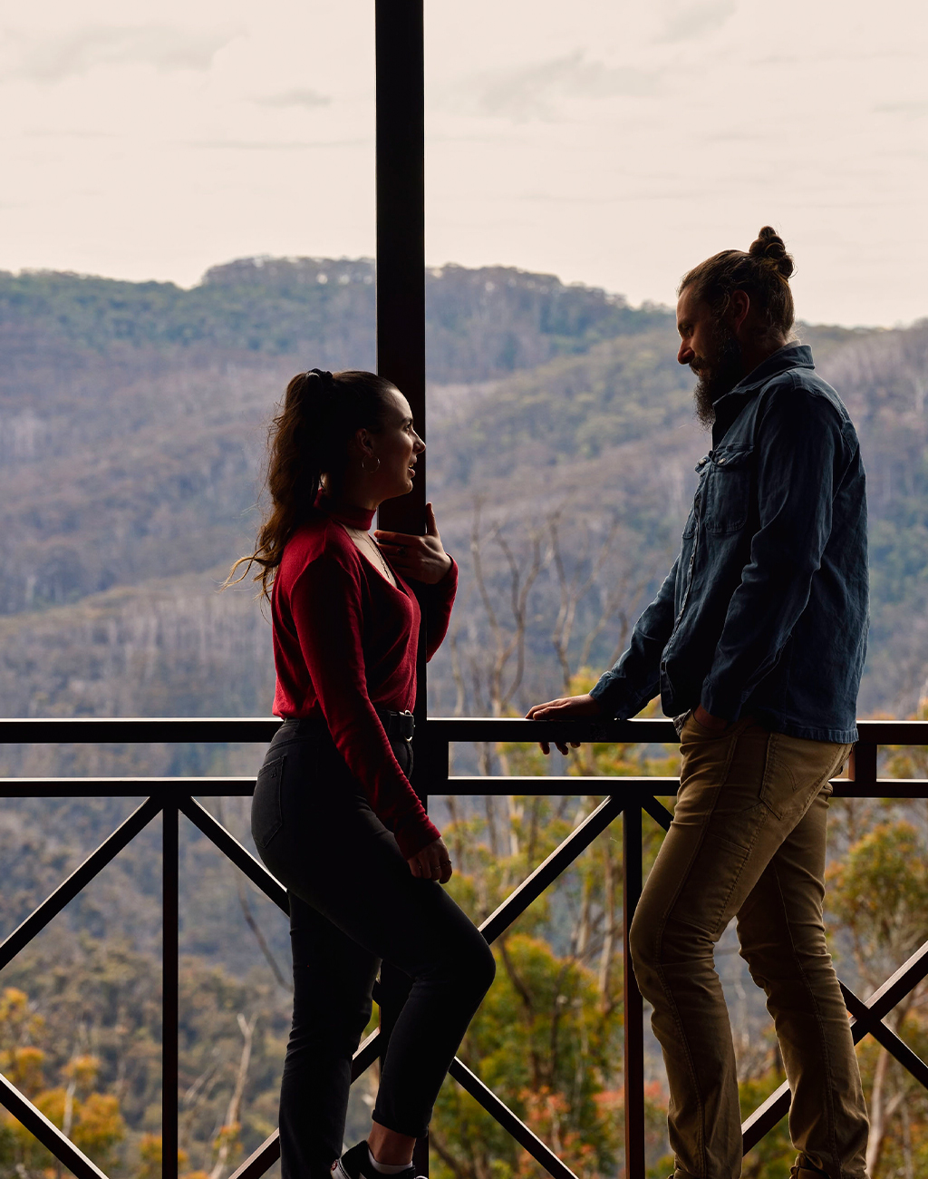 Two people talking on a rustic deck with sweeping mountain views