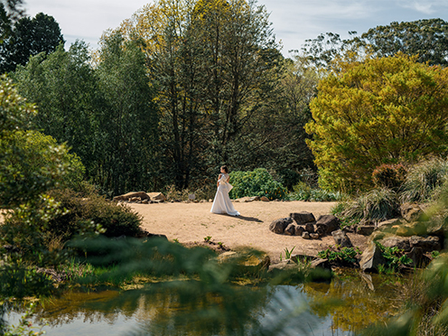 Bride on a sandy clearing next to a pond