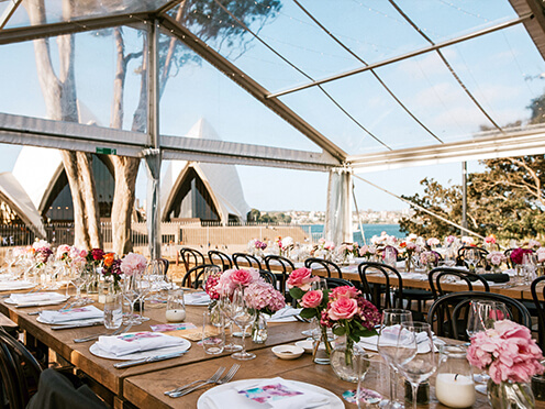 Marquee with elegant dining tables and flowers set up for a wedding, overlooking Sydney Opera House