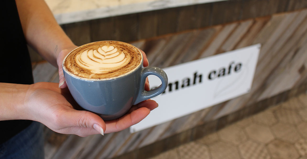 Woman holding coffee at Tomah Cafe