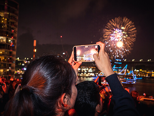 Woman takes a photo of the fireworks over Sydney Harbour on her phone