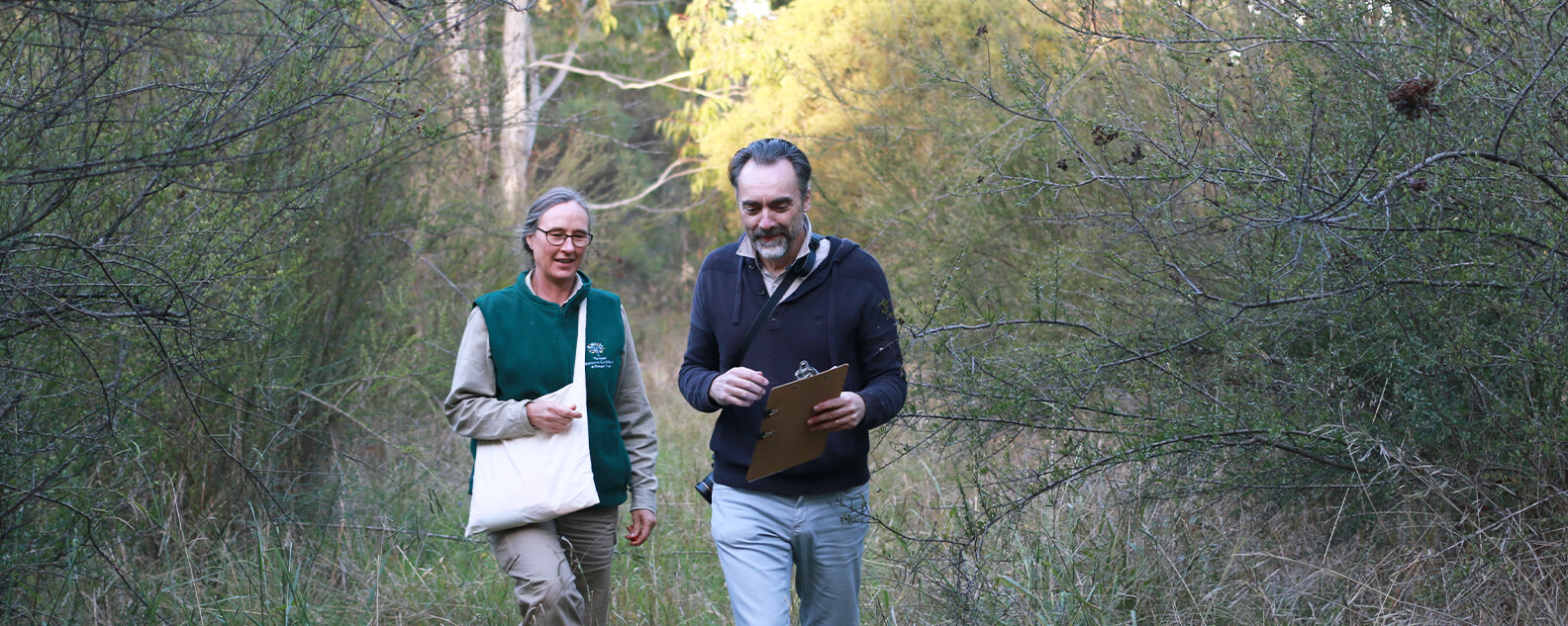 Two scientists with clipboards, in bushland