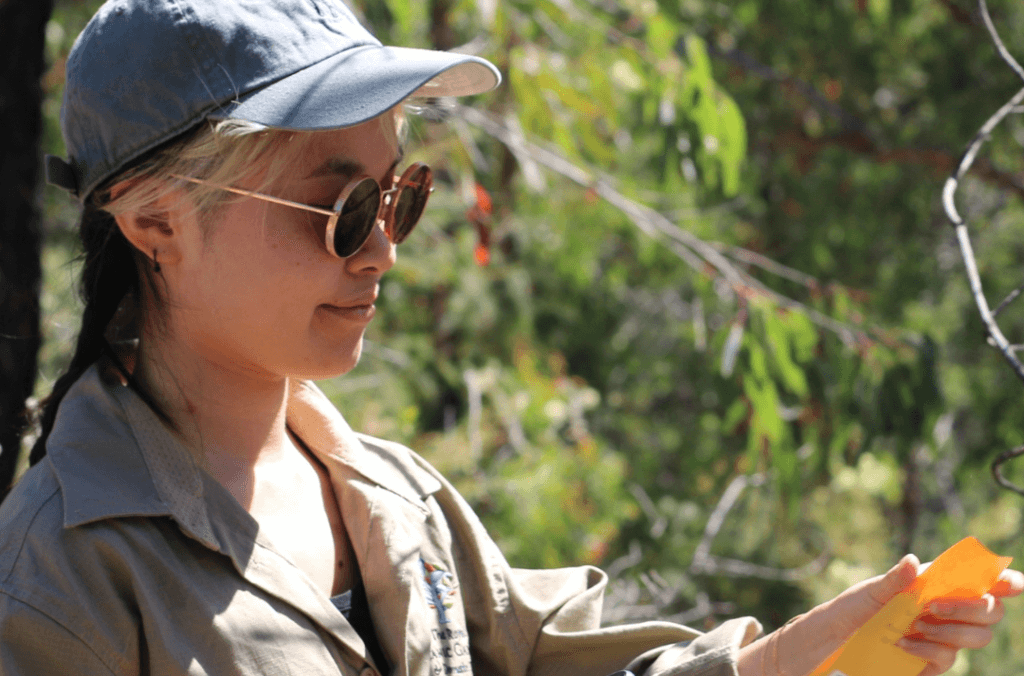 A women with glasses holding an envelope in a garden
