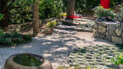Japanese-styled pebbled, shady path with traditional stone and wood water features