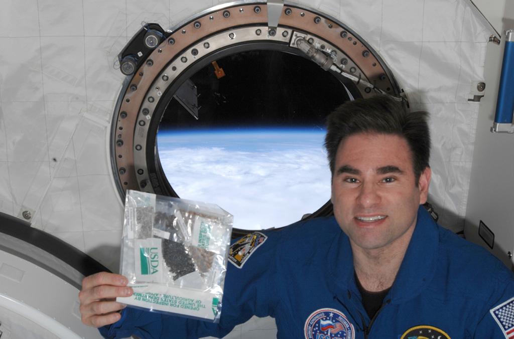 Astronaut in space station with packet of seeds