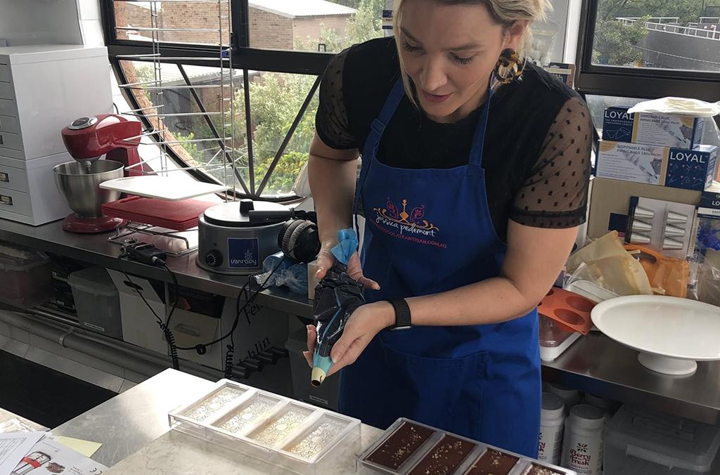 Person piping chocolate into moulds in a kitchen