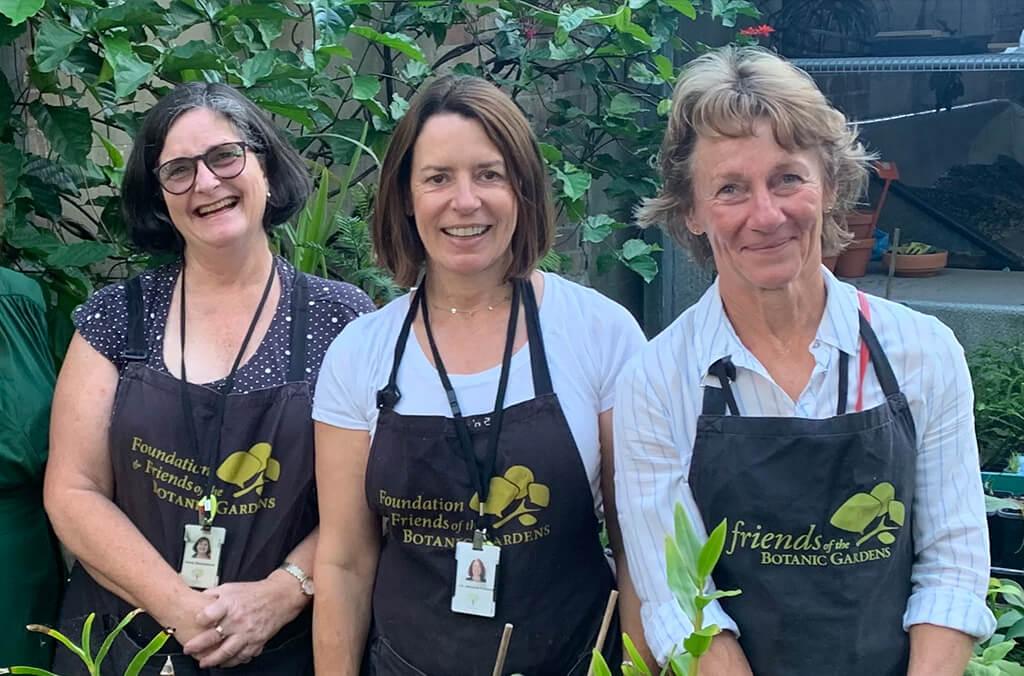 Three smiling women wearing aprons in a nursery