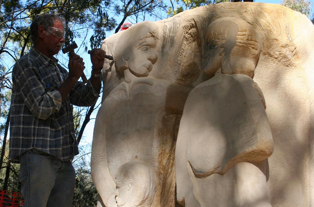Uncle Badger Bates chisels the stone sculpture of a family