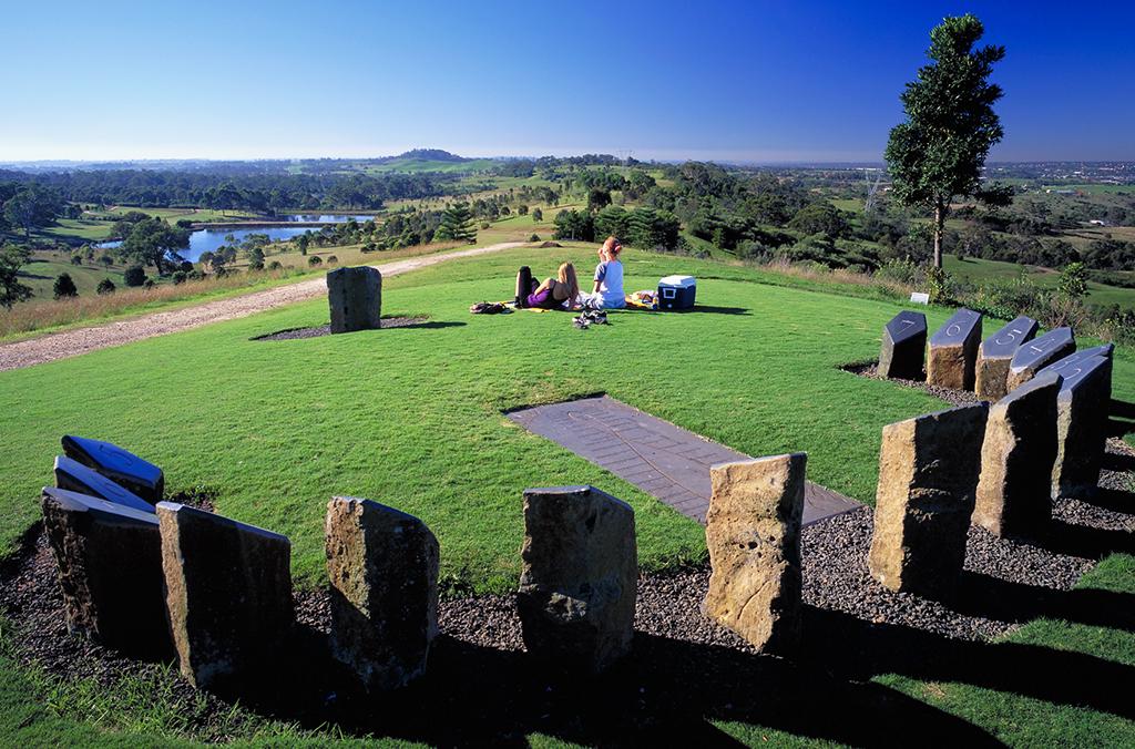 Two picnickers sitting on the lawn at the sundial