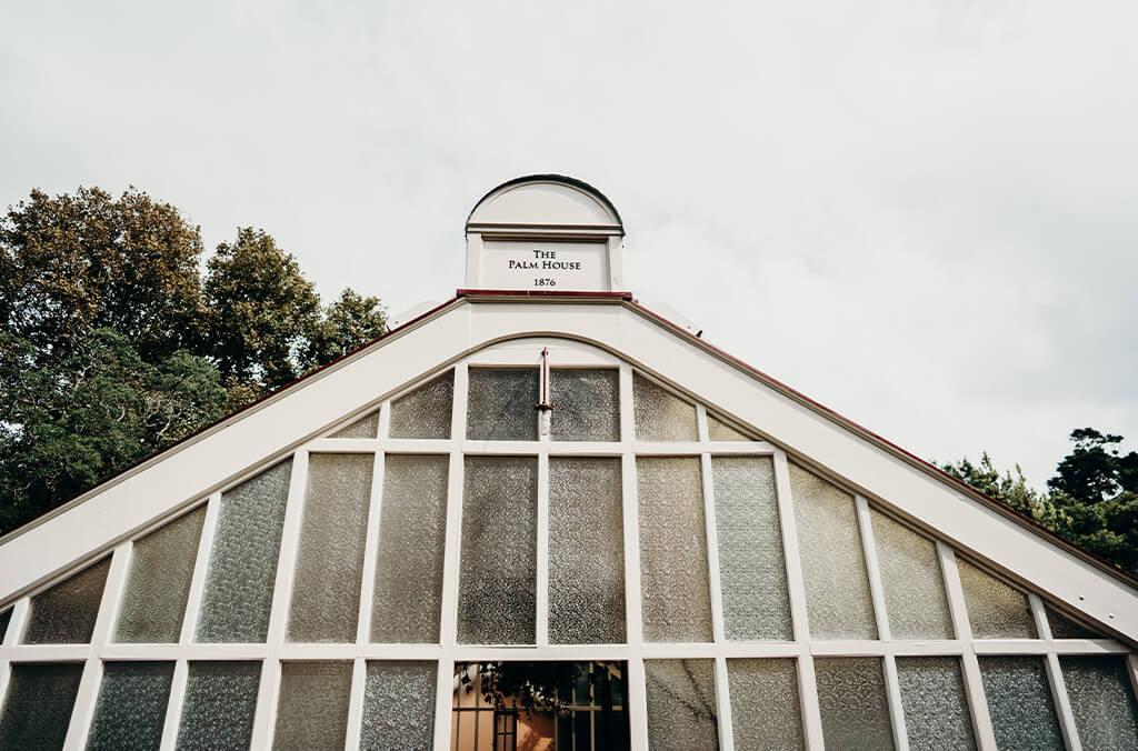 Glass roof of historic Palm House, with white panelling and sign 'Palm House'