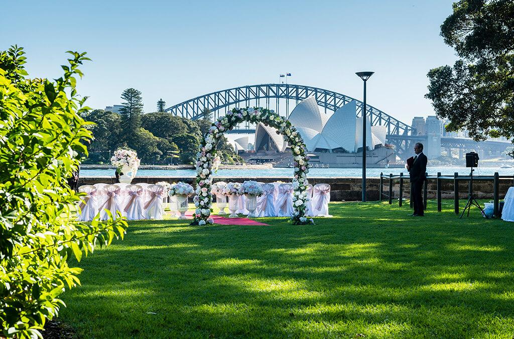 Lawn set up for a wedding ceremony, view over water to the Sydney Opera House and Bridge