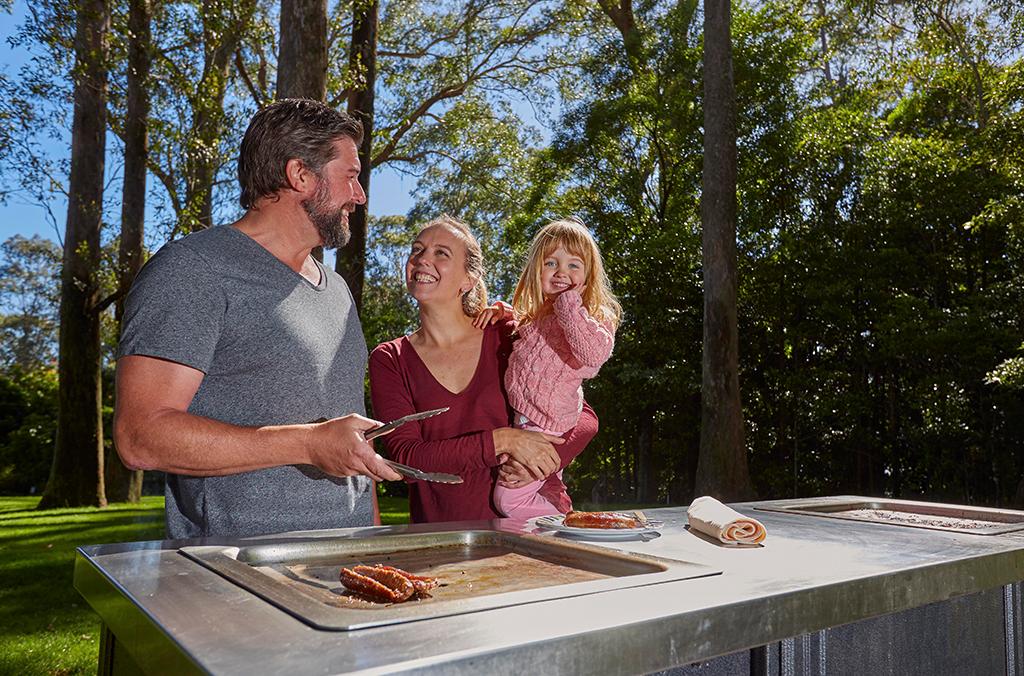 family cooking at an outdoor barbeque