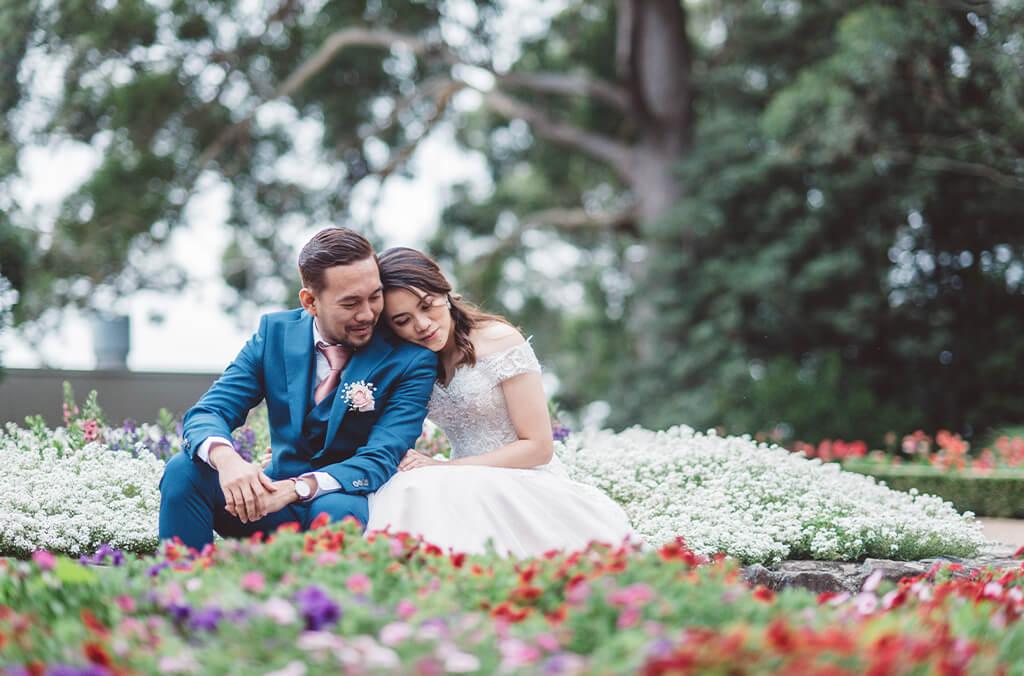 Bride and groom cuddle among bright spring flowers