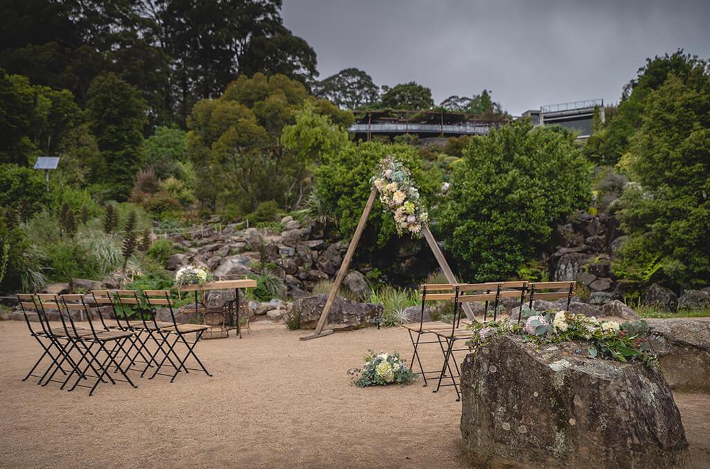 Chairs and floral arch set up for a wedding in a beautiful garden with a pond