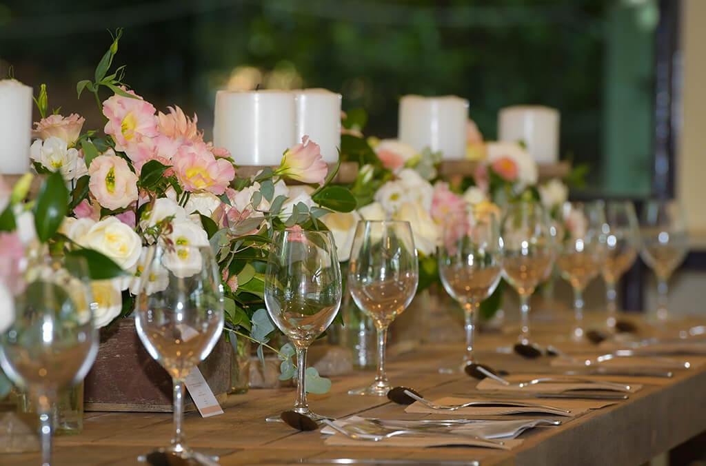 A dining table set with wine glasses, candles and flower centrepieces