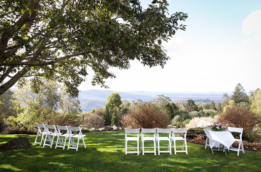 Lawn with large shady tree and mountain views, set up with white chairs