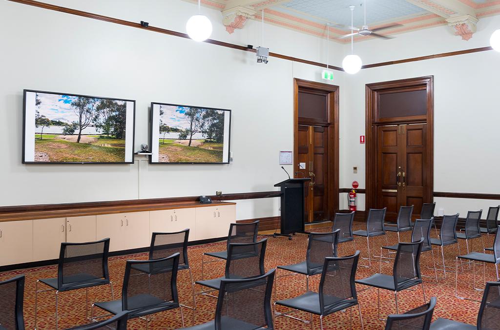 Room with two large screens for presentations, chairs set out for an event
