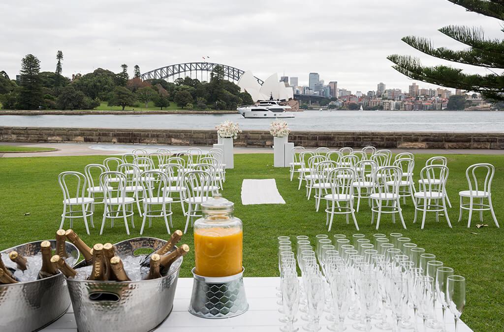 Lawn set up for a wedding ceremony, view over water to the Sydney Opera House and Bridge