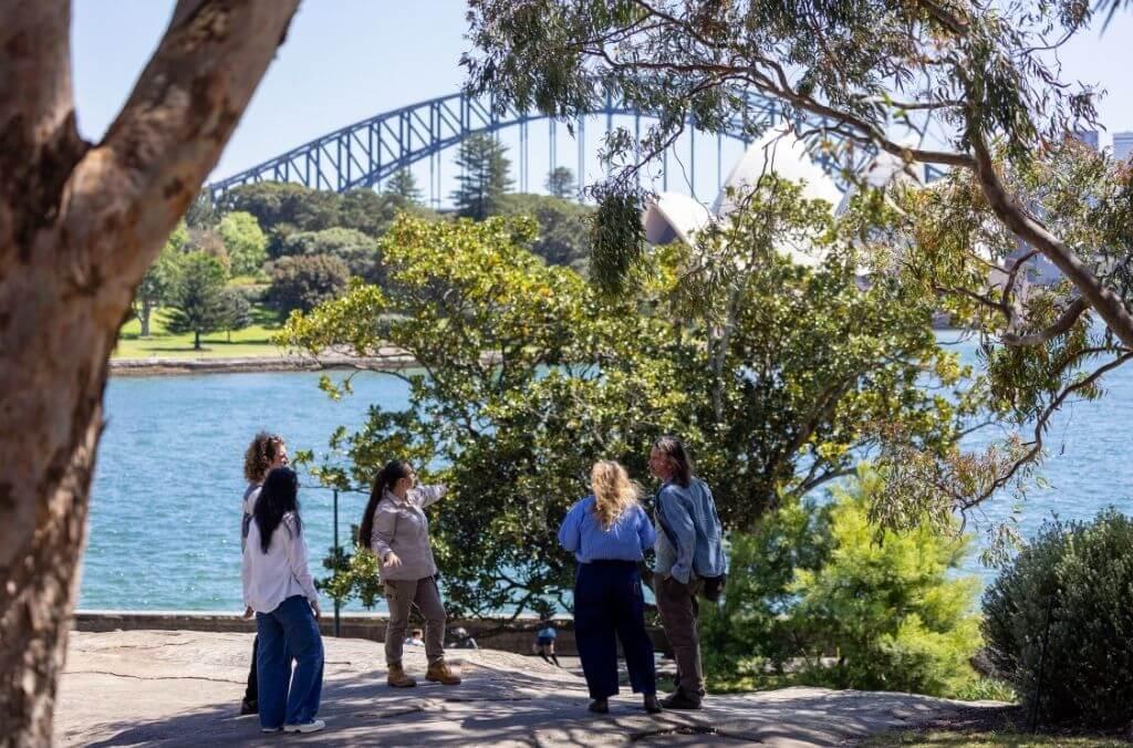 Tour group walking with guide along Sydney Harbour in the Royal Botanic Garden Sydney