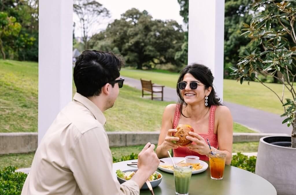Couple enjoying cafe food on sunny outdoor terrace overlooking garden