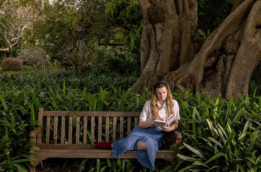 Woman reading a book on a shaded Garden bench