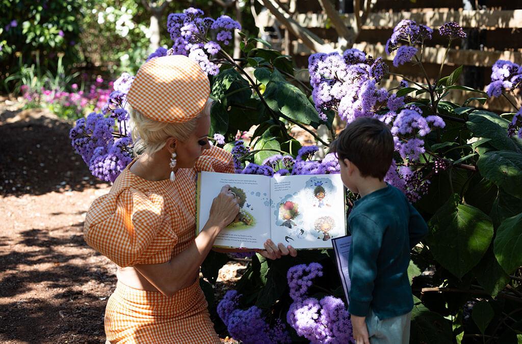 Courtney Act reading to a child